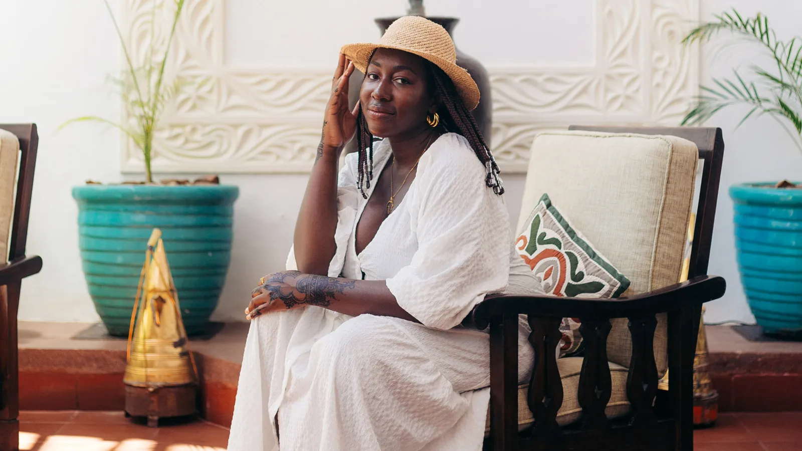 Solo female traveler wearing a white dress and straw hat, relaxing at a boutique hotel in Zanzibar during a safe and stylish solo vacation.