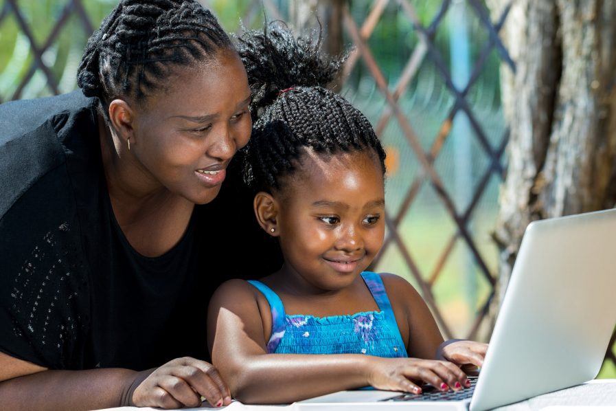 A-teacher-guiding-a-child-on-how-to-use-a-laptop.-Photo-Alamy-897x598