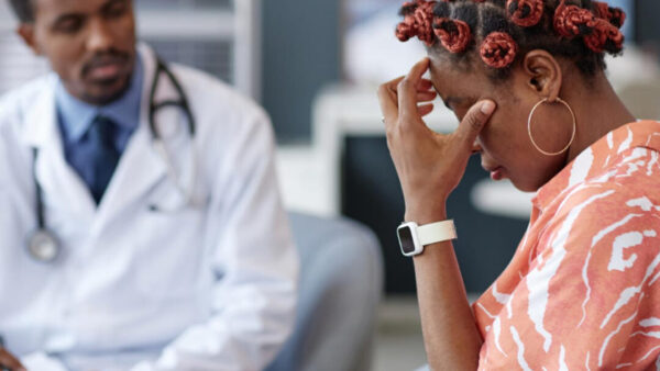 A woman experiencing stress speaks with a doctor during a medical consultation.