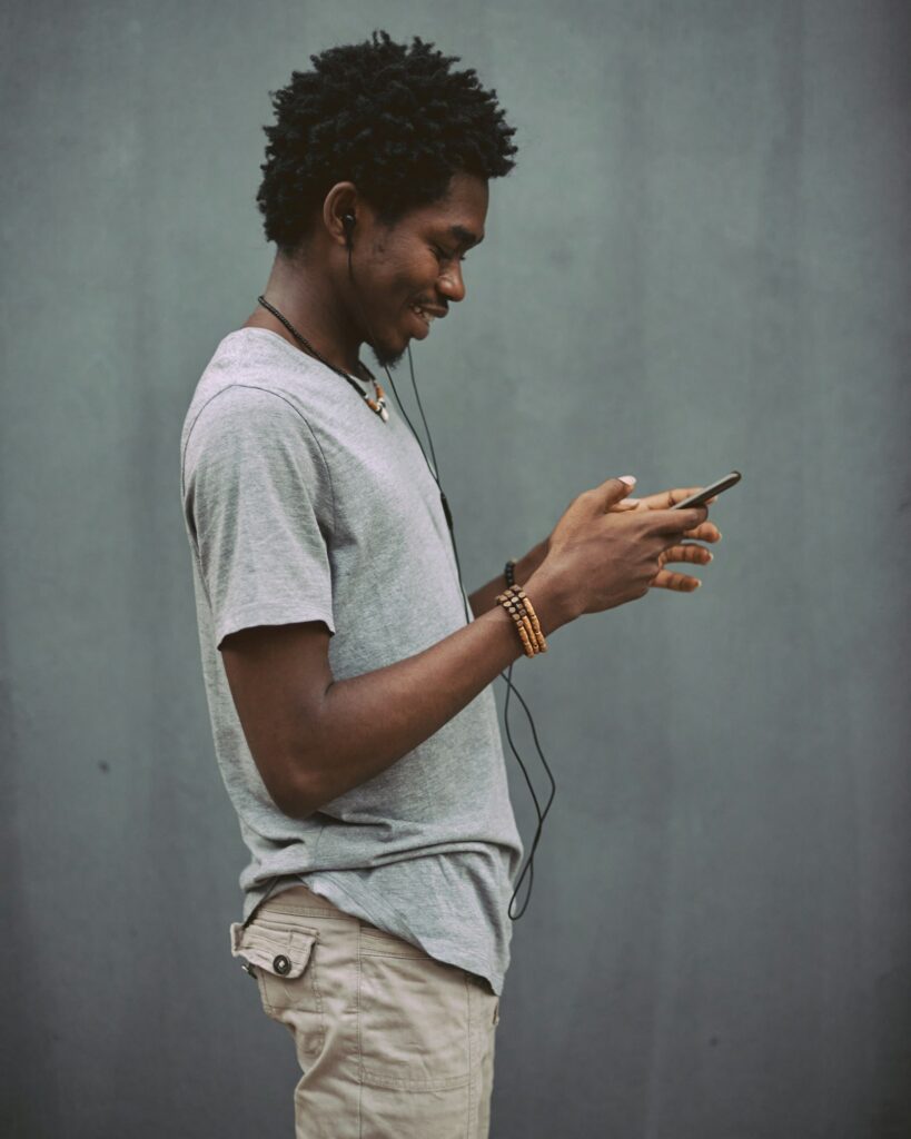 A man in a white t-shirt holding a smartphone