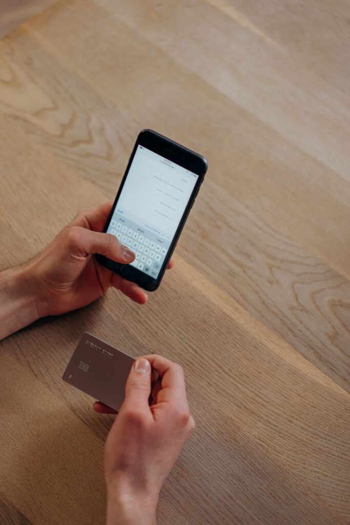 A person making a payment on a smartphone at a wooden table