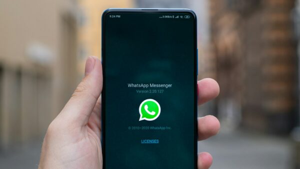 A hand holding an Android phone showing the WhatsApp screen