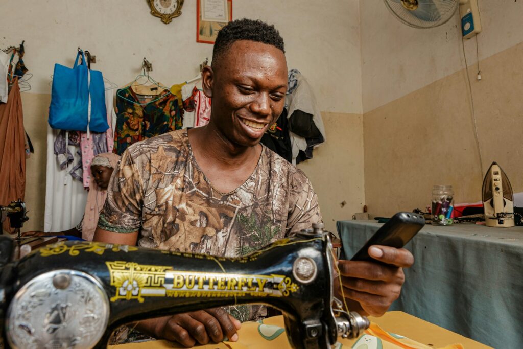 A man smiling as he works at a sewing machine