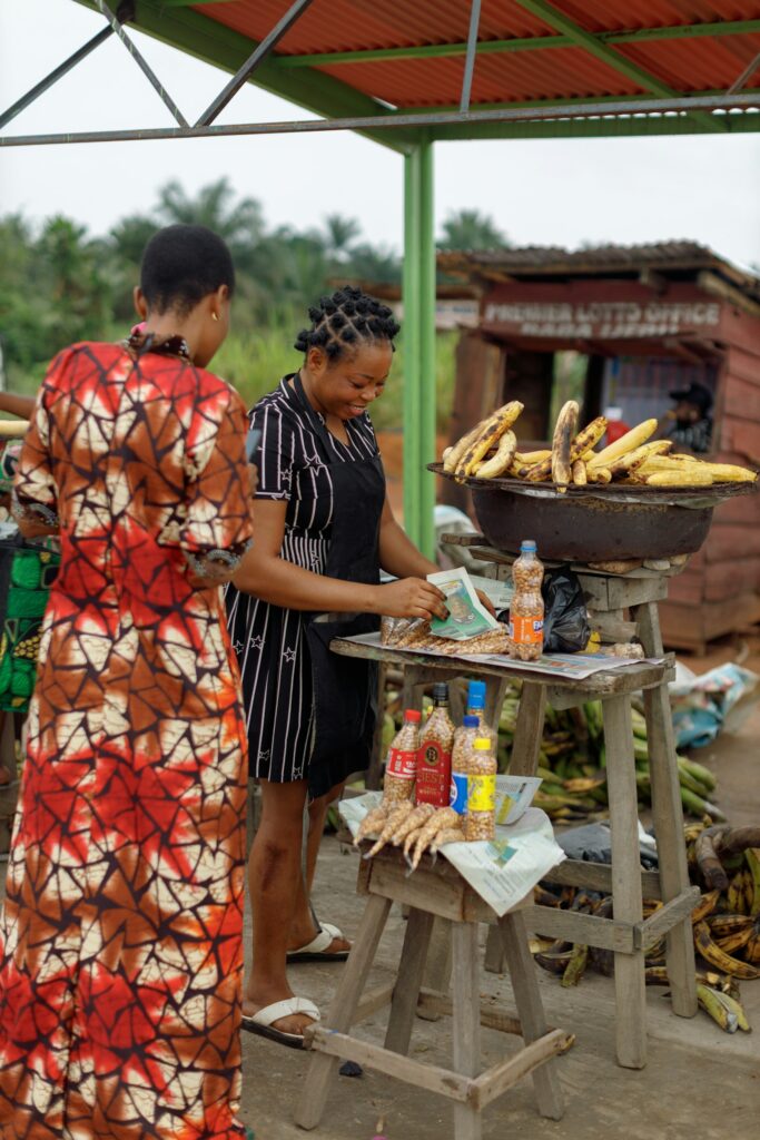 Two women at a food stall selling plantains