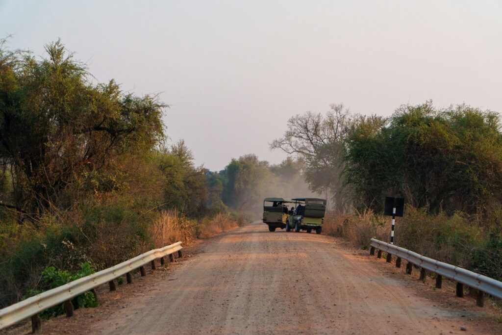 Two vehicles driving on a dusty dirt road