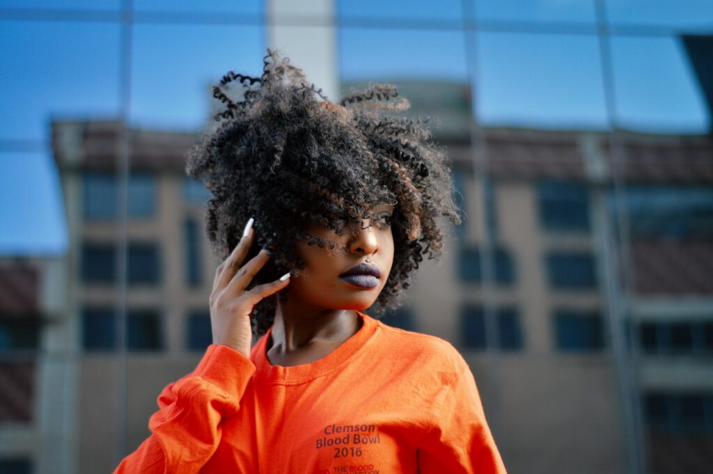 A woman in an orange shirt talking on a mobile phone